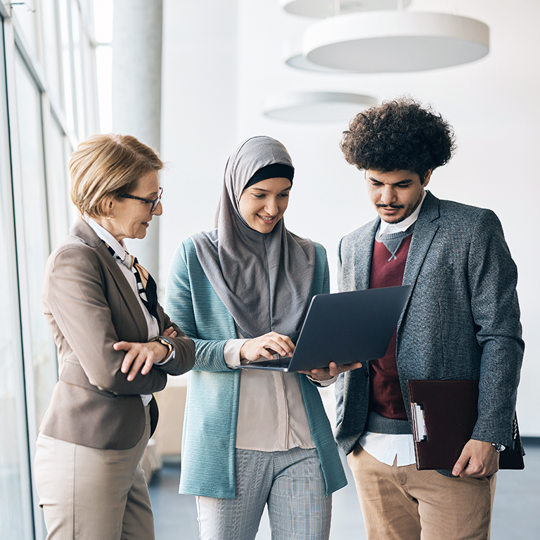 Multiracial group of business colleagues working on laptop at corporate office.